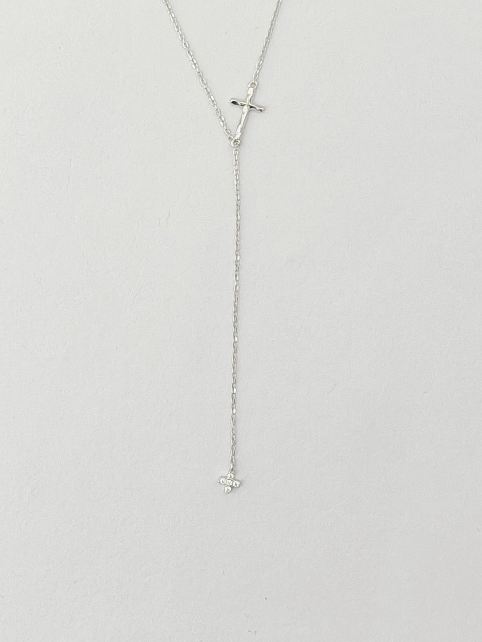 Silver necklace with a cross pendant on a light gray background